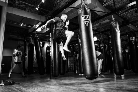 Man jumping up to kick a heavy bag in a gym